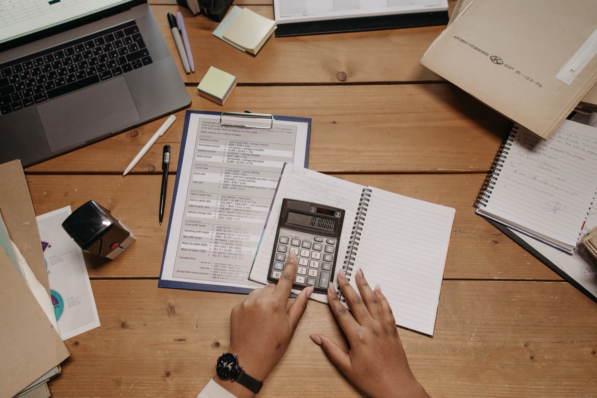 A desk buried in paperwork, receipts, and handwritten notes