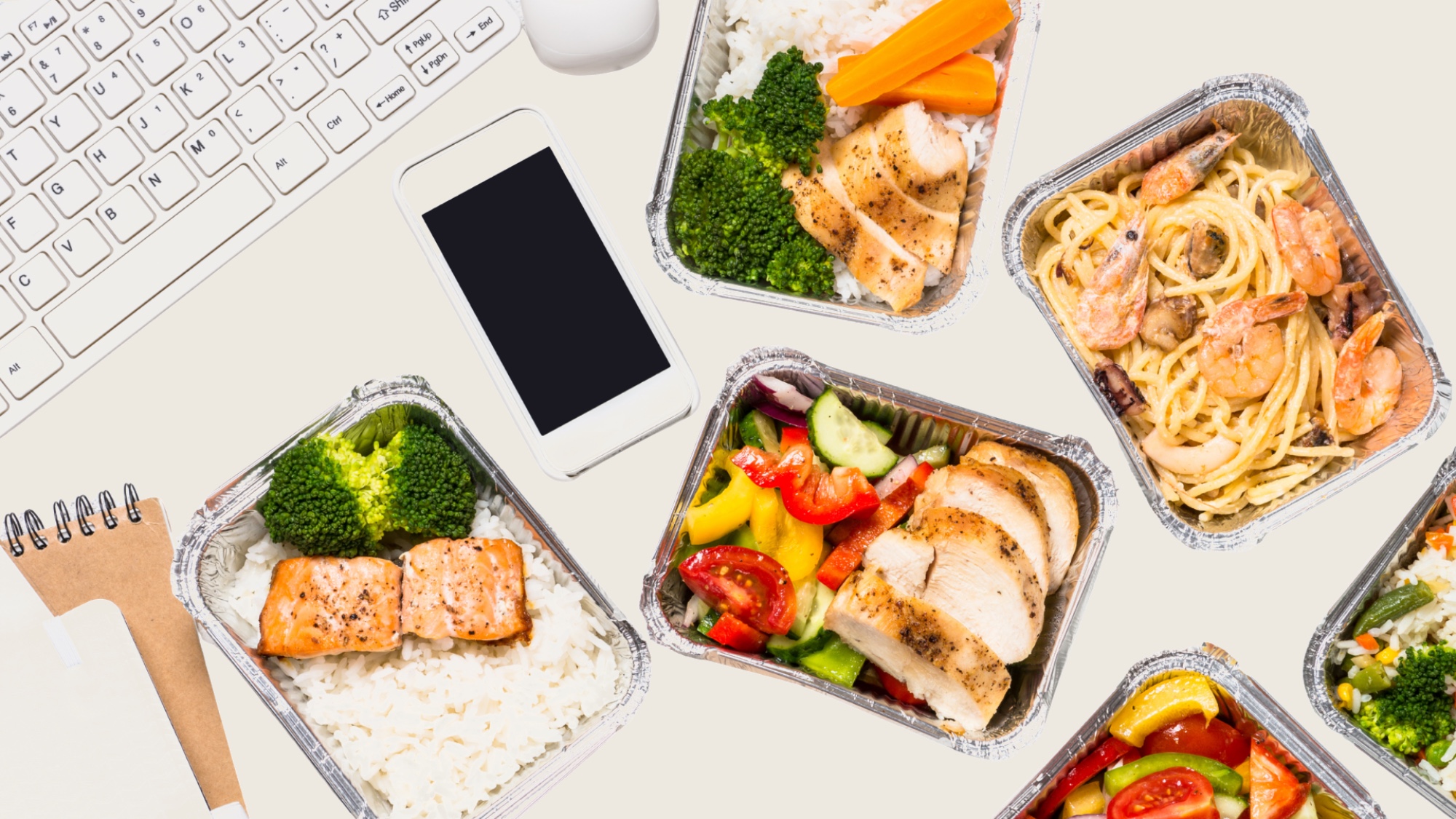 Healthy meal-prep containers with a keyboard and phone on a desk